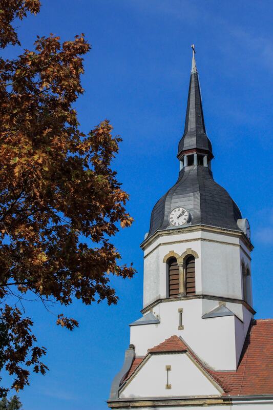 Kirchturm der Dorfkirche Schköna zwischen Herbstlaub