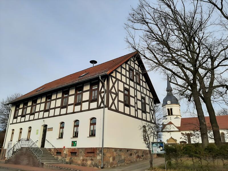 Fachwerkhaus mit Freitreppe, dahinter der Kirchturm, Dezember 2020