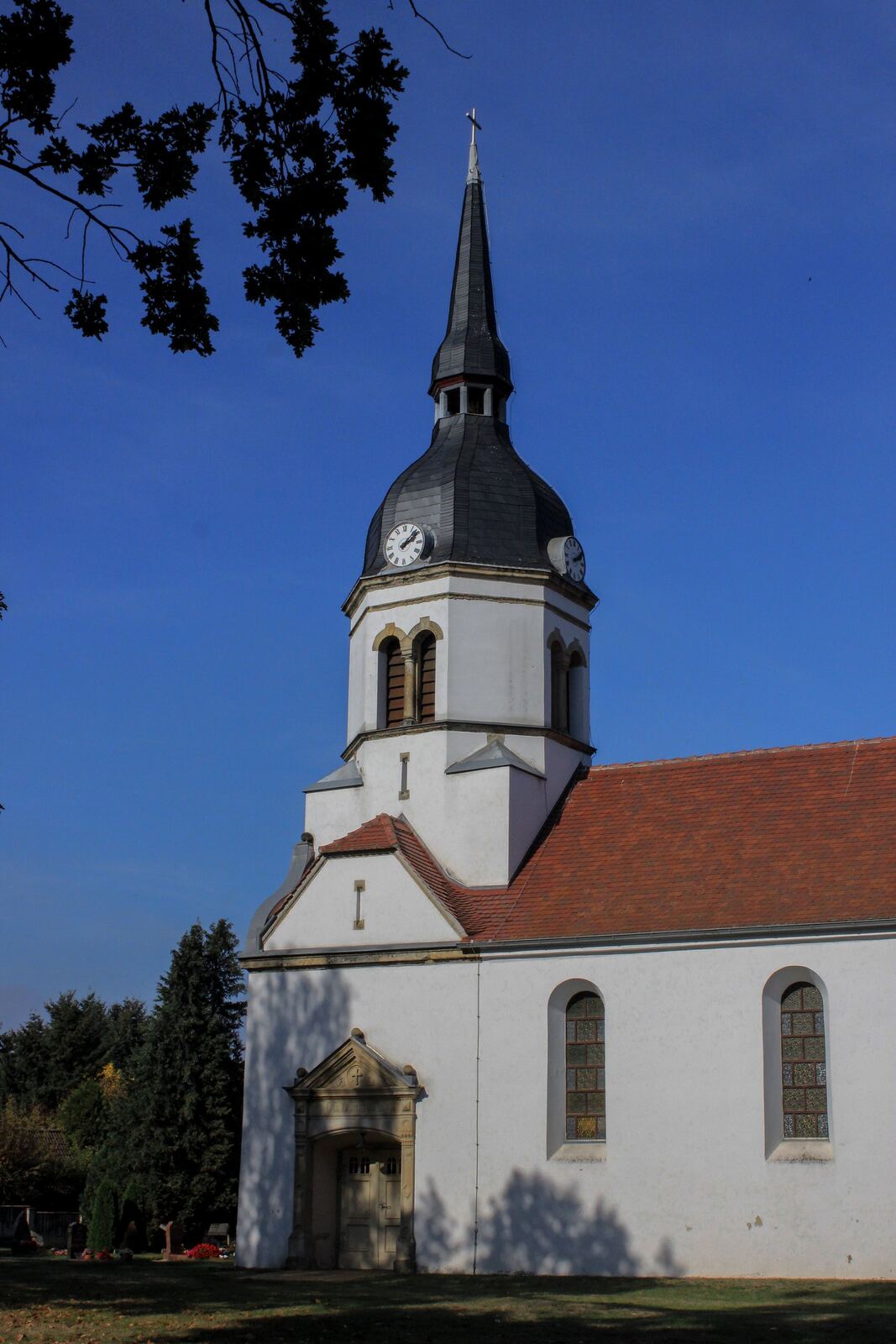 Turm und Kirchenschiff der Dorfkirche Schköna vor blauem Himmel, Oktober 2026