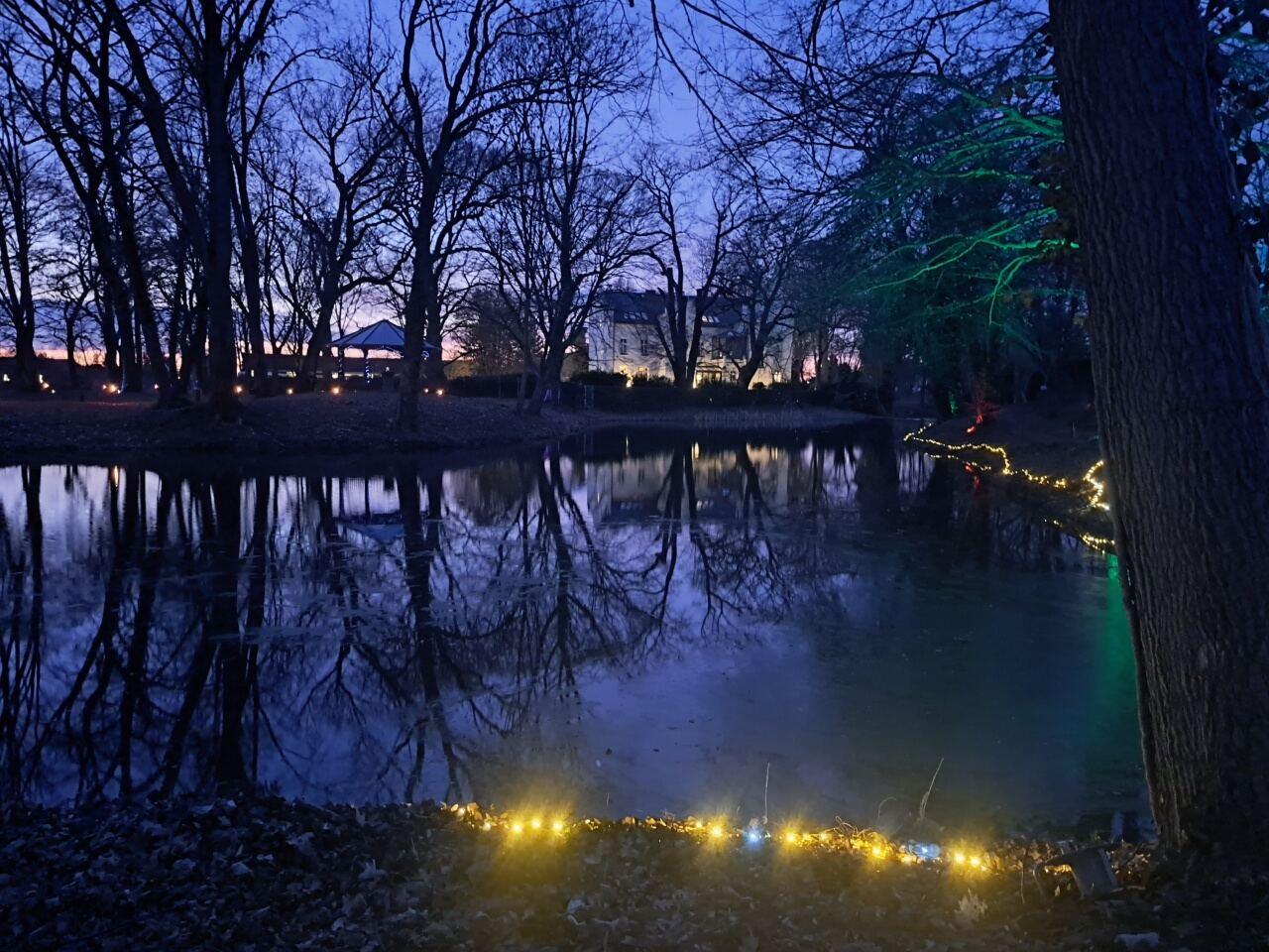 Lichter am Teich im Schlosspark bei Dämmerung